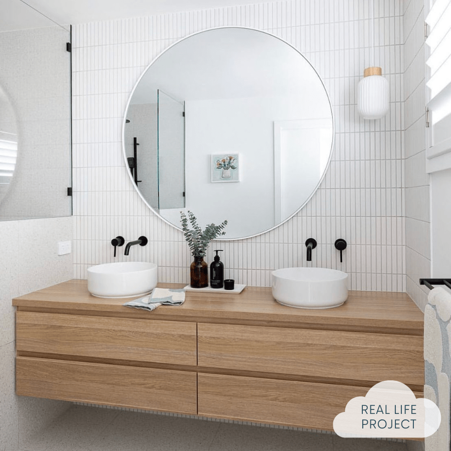 bathroom with white wall tiles, vanity, 2 basins and round mirror